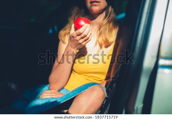 A young\
woman is sitting in a car eating an\
apple