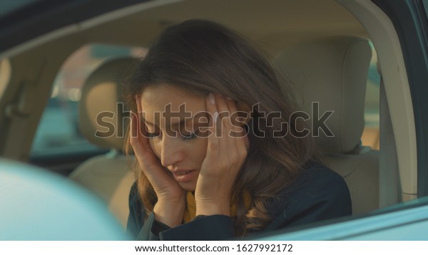 Young woman sitting in car with headache feeling\
sick vehicle influenza health illness flu medical sickness problem\
business infection stress disease medicine exhausted headache slow\
motion