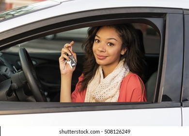Young woman sitting in car holding keys