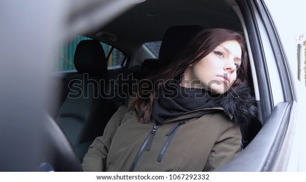 Young\
Woman Sitting in Car Searching Address on\
Street