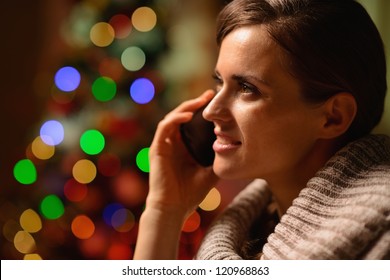 Young Woman Sitting Chair And Making Phone Call In Front Of Christmas Lights