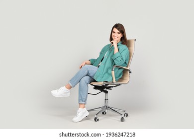 Young woman sitting in comfortable office chair on grey background - Shutterstock ID 1936247218