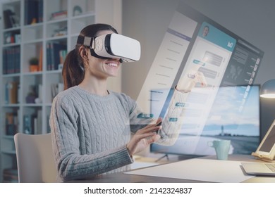 Young woman sitting at desk and interacting with her virtual desktop, she is chatting with her friends and smiling - Powered by Shutterstock