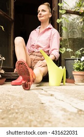 A Young Woman Sitting At The Garden Shed In Her Garden.
