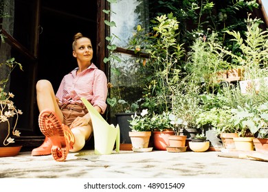 A Young Woman Sitting At The Garden Shed In Her Garden.
