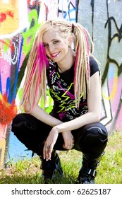 Young Woman Sitting At Graffitti Wall