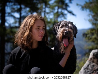 Young woman sitting with her pet dog with her hand around his neck. 