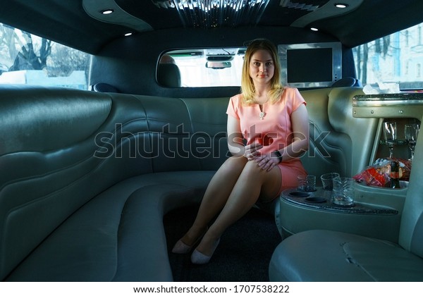 A young woman is\
sitting in a limousine.