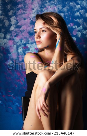 Young woman sitting near painting wall