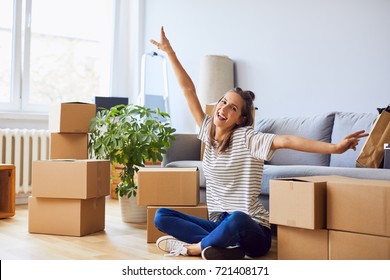 Young woman sitting in new apartment and raising arms in joy after moving in - Powered by Shutterstock