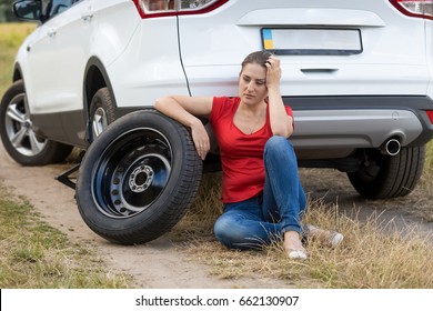 Young Woman Sitting Next To The Car With Flat Tire