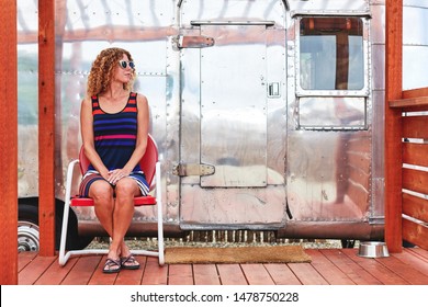 a young woman sitting next to a vintage camper