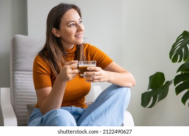 Young Woman Sitting On An Armchair Drinking Coffee At Home. Leisure Activity, Lifestyle For People Concept.
