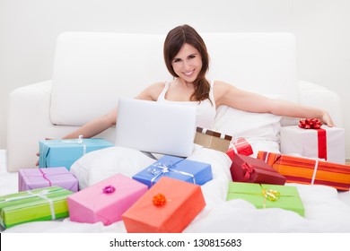 Young Woman Sitting On Bed And Shopping Online