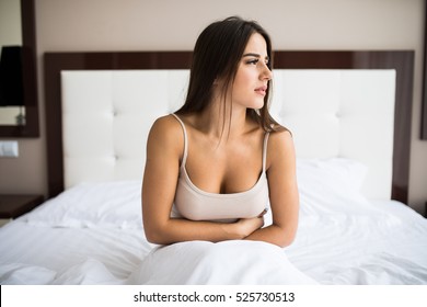 Young Woman Sitting On The Bed With Pain