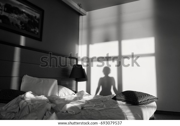 若い女性がベッドに座り 壁に影を落としている 白黒の窓の前にある女の子のシルエット モノクロ写真 レトロ の写真素材 今すぐ編集