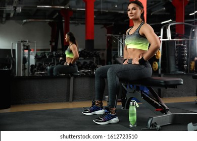 Young Woman Sitting On Bench In Modern Gym