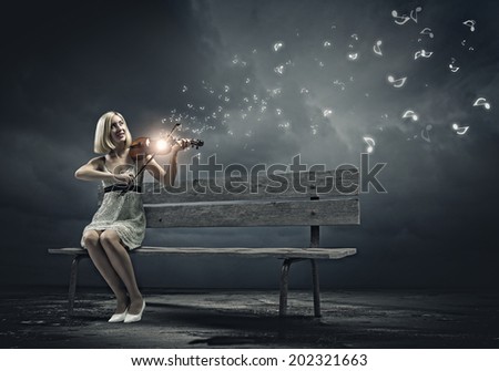 Young woman sitting on bench and playing violin