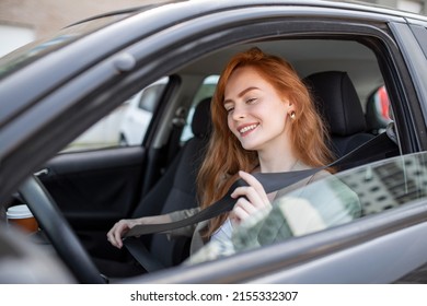 Young woman sitting on car seat and fastening seat belt, car safety concept. Woman fastens a seat belt in the car. Caucasian woman driver fastening car seat belt while sitting behind the wheel 