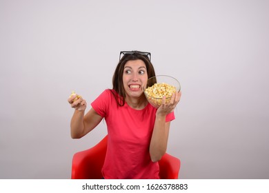 young woman sitting on a chair with popcorn watching a movie - Shutterstock ID 1626378883