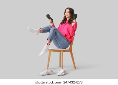 Young woman sitting on chair and holding orthopedic insoles isolated on white background