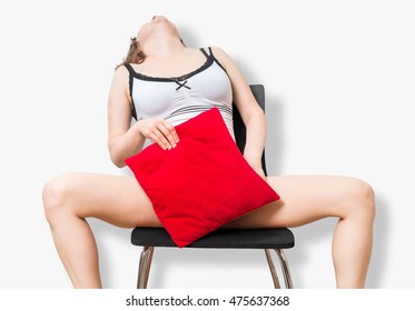 Young woman is sitting on chair, masturbating and covering with red pillow.