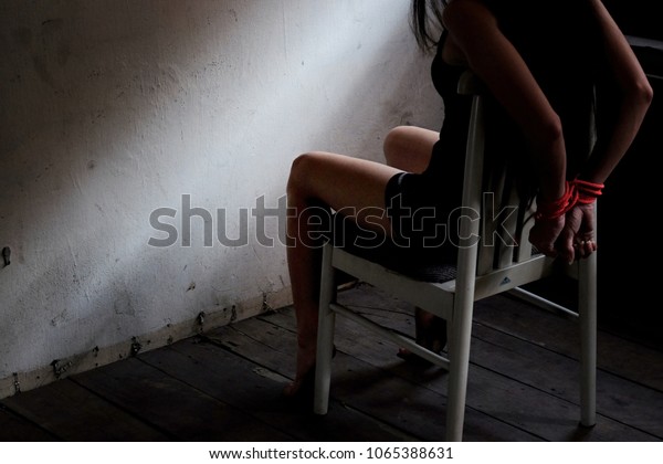 Young woman sitting on chair and tied up with rope.
