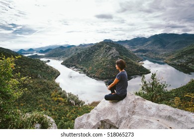 Young woman sitting on cliff's edge and looking to beautiful view - Shutterstock ID 518065273