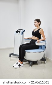 Young woman sitting on electromagnetic chair for stimulation of deep pelvic floor muscles and restoring neuromuscular control at the clinic - Shutterstock ID 2170611061