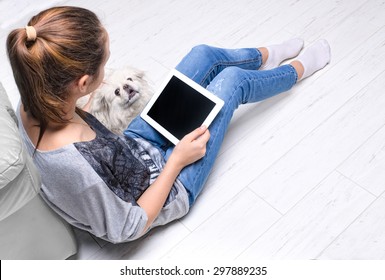 Young Woman Sitting On Floor And Using Tablet .