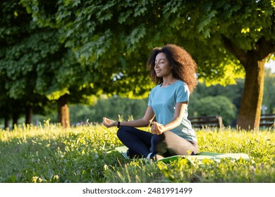 Young woman sitting on grass in park, meditating with closed eyes. Relaxation, mindfulness, and yoga practice in nature. Peaceful and serene outdoor setting. - Powered by Shutterstock