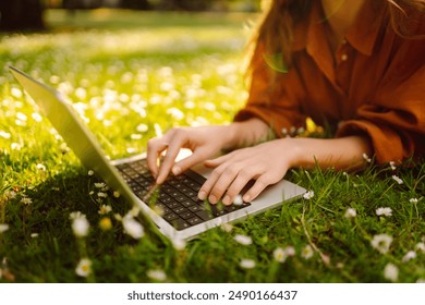 Young Woman sitting on grass ground, working on laptop pc computer in city park on green grass sunshine lawn outdoors. Mobile Office. Freelance business concept - Powered by Shutterstock