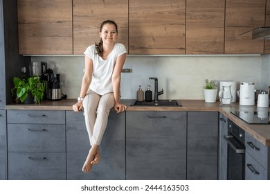 Young woman sitting on her kitchen counter at home. High quality photo - Powered by Shutterstock