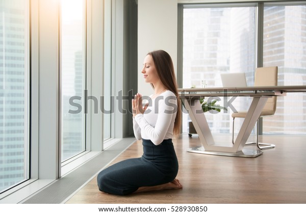 膝をついて座る若い女性 オフィスヨガ 正座の練習 机の仕事の不快感を最小限に抑え 仕事に集中しやすく 真剣な打ち合わせの後のリラックス の写真素材 今すぐ編集