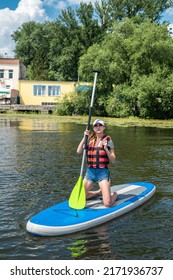 Young Woman Sitting On Paddle Board Wear Life Vest And Learn How Swim, Summer Active Lifestyle