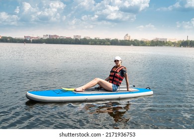 Young Woman Sitting On Paddle Board Wear Life Vest And Learn How Swim, Summer Active Lifestyle