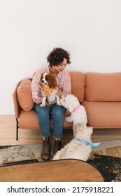 Young Woman Sitting On Sofa With Her Three Dogs