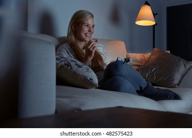 Young Woman Sitting On Sofa, Watching Tv, Eating Chocolate