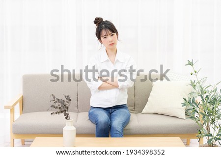 A young woman sitting on a sofa by the window and thinking