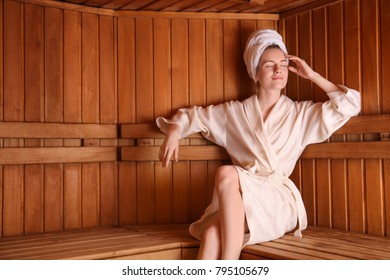 Young Woman Sitting On Wooden Bench In Sauna