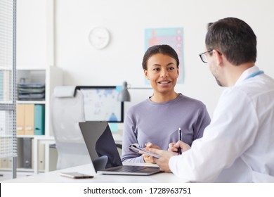 Young Woman Sitting Opposite The Doctor And Talking To Him While Sitting At His Office