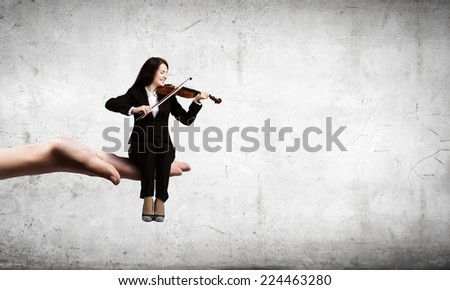 Young woman sitting in palm and playing violin