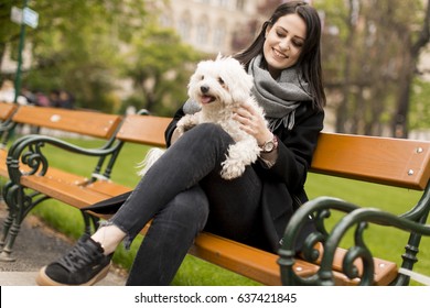 Young woman sitting in the park and holding a small dog in her lap - Powered by Shutterstock