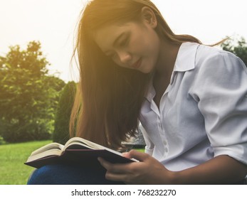 Young woman sitting reading book at the park. - Shutterstock ID 768232270