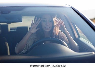 Young woman sitting scared in car.