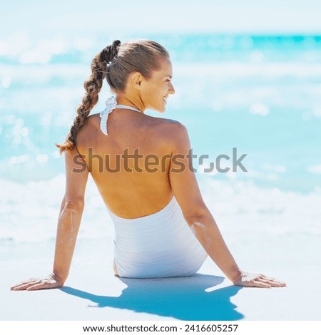 Young woman sitting at seaside and looking on copy space. rear view