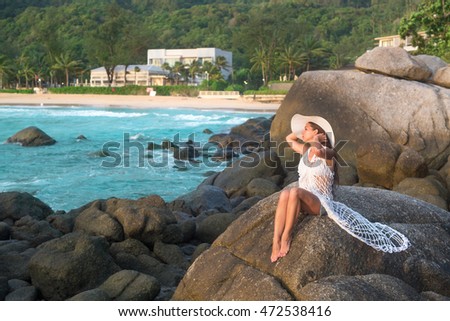 Young woman sitting at stone near ocean