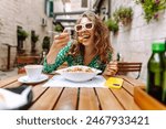 Young woman sitting in summer cafe, eating pasta with tomato, meat. Bolognese. Parmesan cheese. Travel, tourism, food and drink.