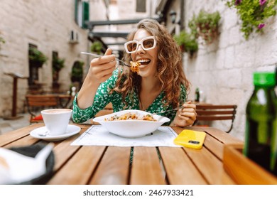 Young woman sitting in summer cafe, eating pasta with tomato, meat. Bolognese. Parmesan cheese. Travel, tourism, food and drink.