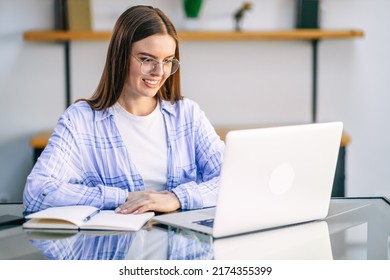 Young woman sitting at table at home working using laptop computer with happy face with confident smile.